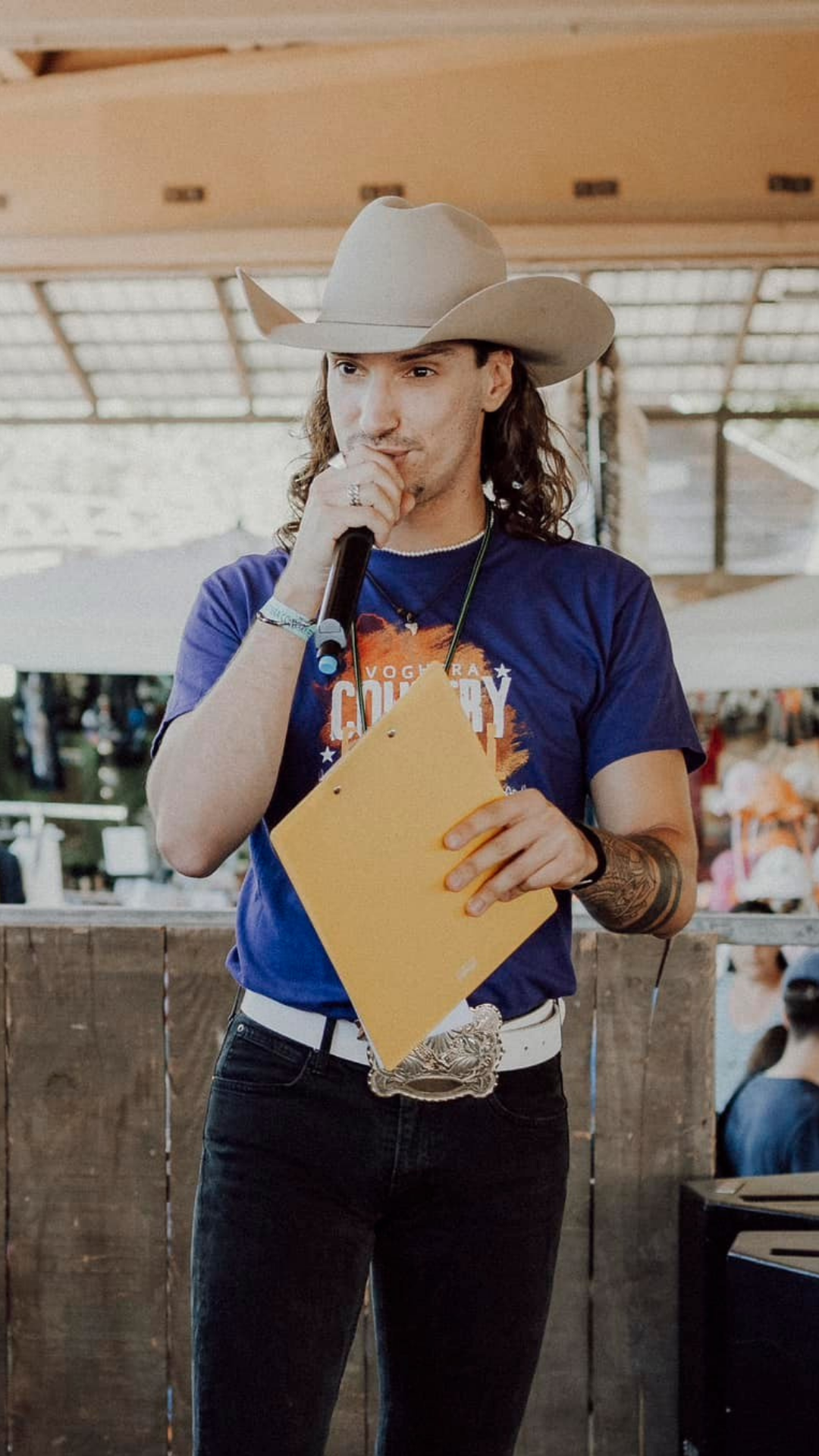 Johnny Rossato holding a microphone on stage at the Voghera Country Festival