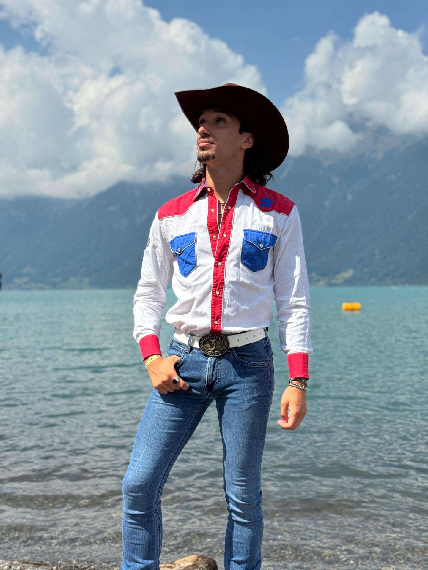 Johnny Rossato standing by a mountain lake in a red, white and blue western shirt
