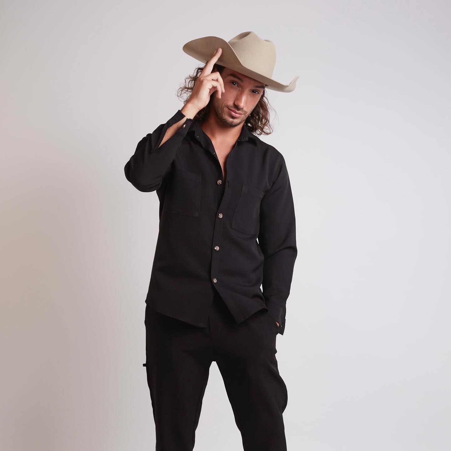 Johnny Rossato in a black shirt tipping his cowboy hat